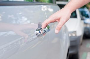 A person attempting to open a car door handle